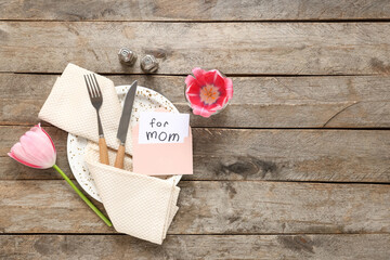 Table setting with greeting card for Mother's day and tulip on wooden background