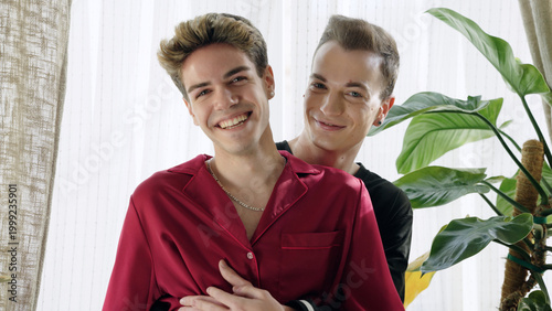 Photos Happy gay couple embracing indoors, smiling at camera
