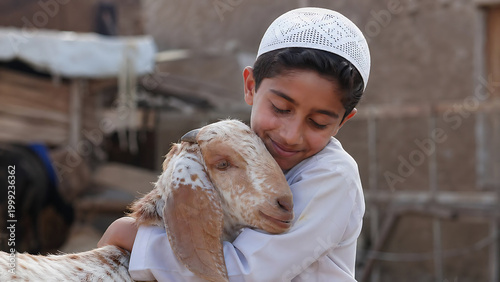 A young boy in a white cap lovingly embraces a goat, sharing a tender moment of connection and affection.