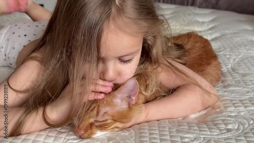 Little girl  is smiling and stroking ginger cat at home. Love pet concept, pet care concept