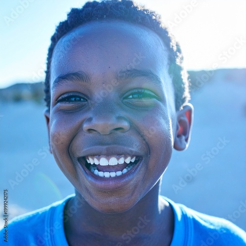 close up image of a young black boy laughing as sunlight hits his face,  soft golden  