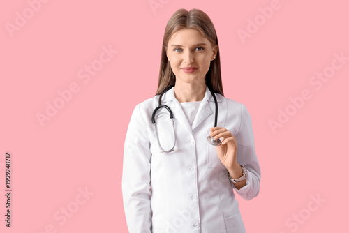 Beautiful young doctor on pink background