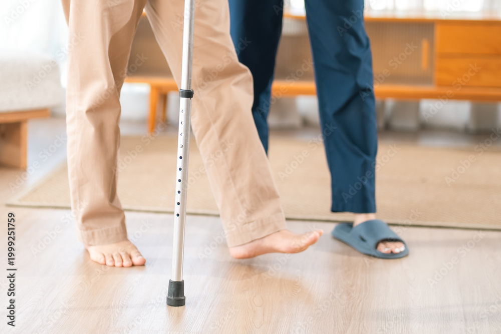 Fototapeta premium Caregiver with Asian senior patient, cane walking foot leg balance rehabilitation indoor person support therapy
