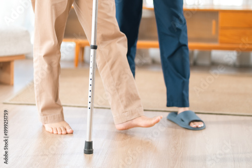 Caregiver with Asian senior patient, cane walking foot leg balance rehabilitation indoor person support therapy
