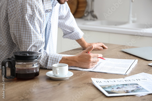 Young man reading newspaper...