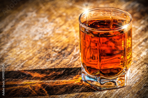 Glass of old whiskey on the table in sunny day