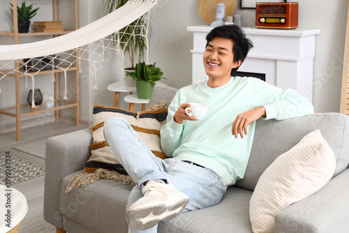Young Asian man with cup of...