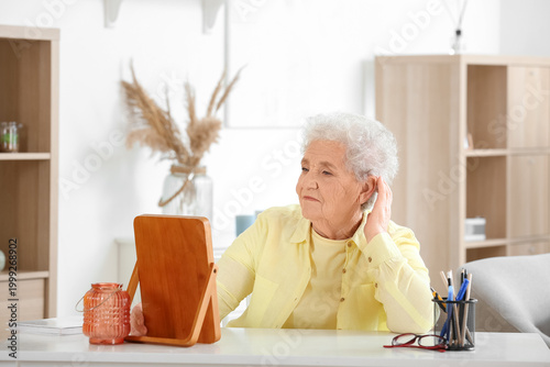 Senior woman looking in mirror at home