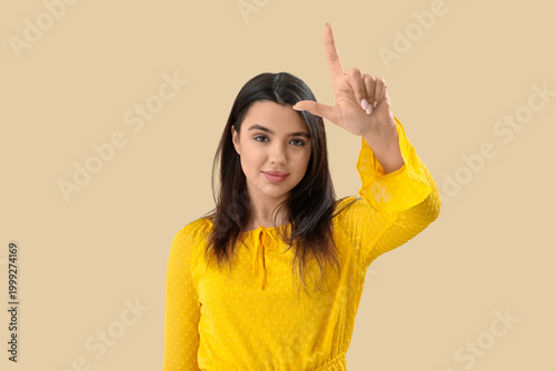 Foto Young woman showing loser gesture on beige background
