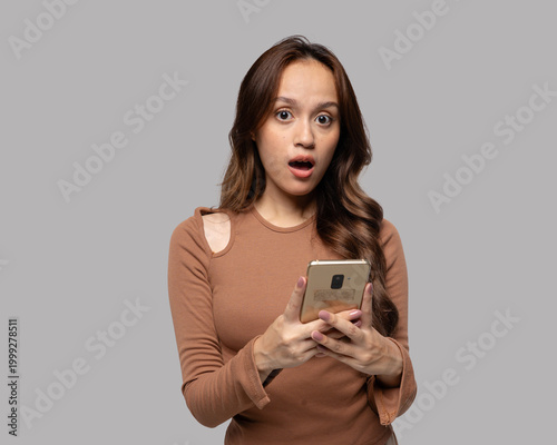 Surprised young woman looking at smartphone with shocked expression