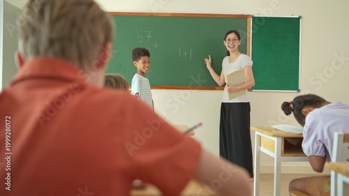 Schoolgirl solving math problem on chalkboard with teacher guidance in classroom, representing education and problem solving