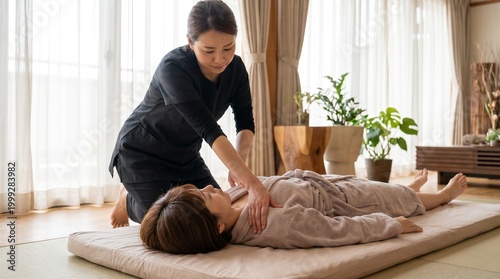  Shiatsu Japanese women receiving a relaxing massage on a mat in a serene room with a therapist