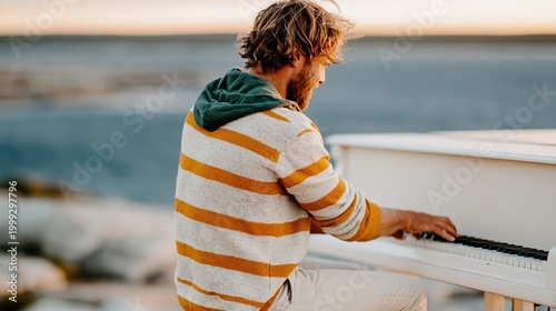 A relaxed man plays a white piano by the ocean, capturing a serene moment of musical expression surrounded by nature's beauty at sunset.