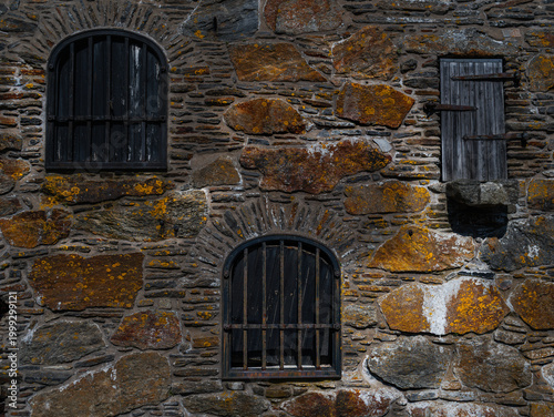 Old stone wall with barred windows, rustic architecture texture