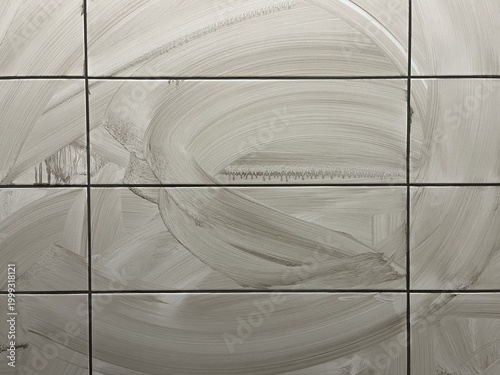 A detailed macro view of newly installed white ceramic wall tiles covered in a thick layer of wet, grey joint grout. The surface exhibits chaotic, circular smear marks left by a sponge or trowel