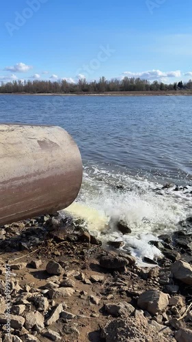 Sewage water flowing from pipe into river, wastewater discharge causing environmental pollution and water contamination