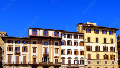 Classic Florentine Residential Building Facades With Traditional Wooden Shutters And Wrought-Iron Balconies Against A Clear Deep Blue Sky On A Sunny Summer Day In Italy