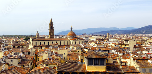 Florence Italy Panoramic Cityscape With A Church Campanile And Duomo Under Blue Skies With Terracotta Tiled Roofs And Buildings