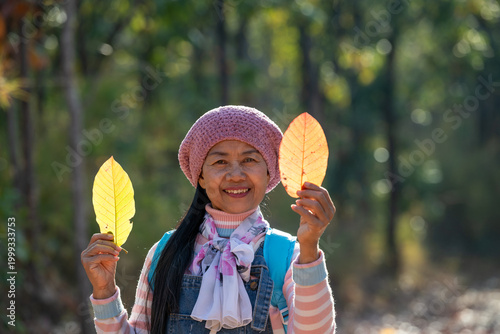 Foto Asian Woman Holding Golden Autumn Leaves In A Peaceful Forest During A Seasonal