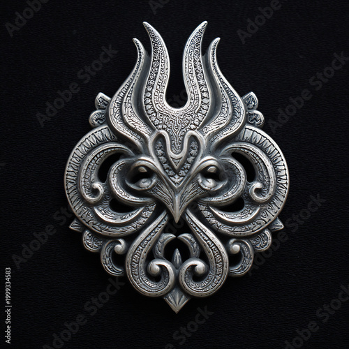 Ornate silver medallion with intricate symmetrical scrollwork and stylized botanical motif on a textured dark background