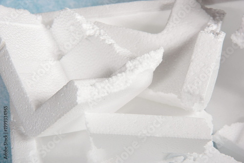 Styrofoam Sheets of different shapes on blue background. Pieces of white styrofoam close up