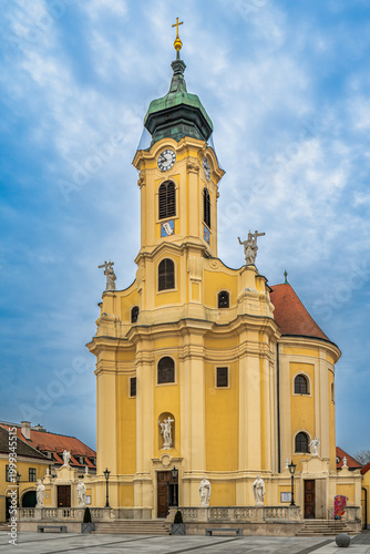 Baroque church facade tower with clock and statues in Laxenburg