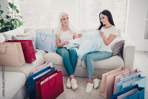 Foto Mother and daughter trying on clothes together at home surrounded by colorful sh