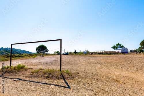 Soccer football dirt dry field with gate at Perdiki mountain village on Ikaria island, Greece rural countryside small town at longevity blue zone