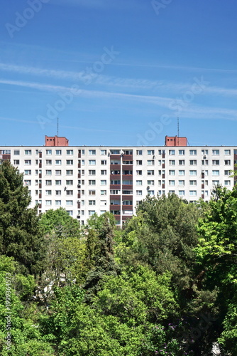  Vertical View of a Large Residential Apartment Building Behind Lush Green Trees, Eastern European Panel Block Housing Estate, Urban Living and Real Estate Architecture in Green City Environment