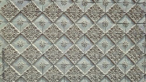 Fotografie Traditional Thai floral relief pattern on yellow sandstone wall, architectural exterior texture of decorative terra cotta tiles, oriental heritage background