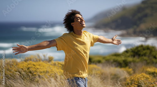Young black man enjoying nature with arms outstretched by the coast  