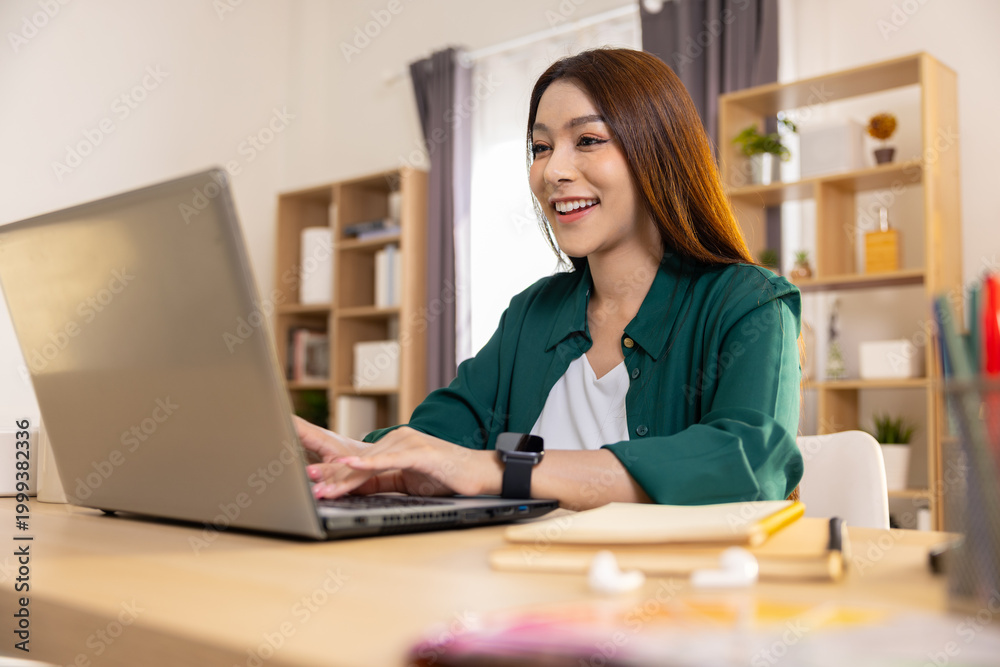 Obraz premium Happy asian woman smile typing laptop computer work home desk online enjoying remote freelance job success cheerful young adult studying education comfortable modern living room