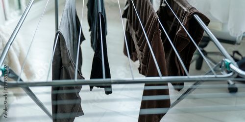 Fotografie Assorted clothing items are draped over a collapsible drying rack inside, symbol