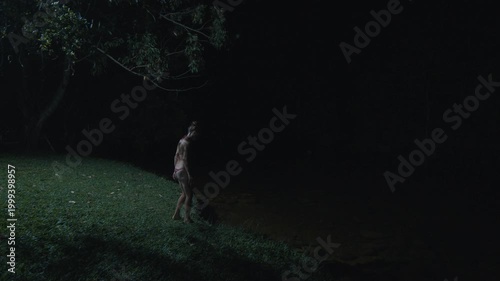Young woman in bikini enters the river and swims at night