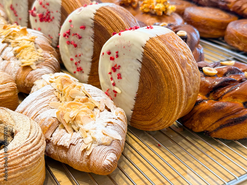 Принти на полотні Laminated pastry rolls dipped in white chocolate with raspberry pieces arranged on bakery rack