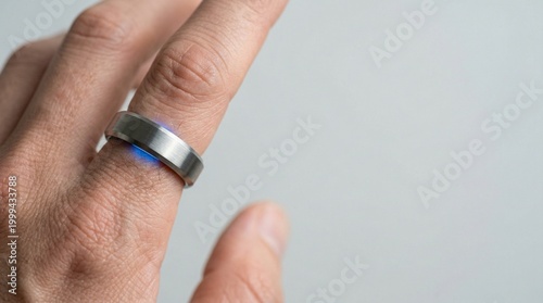 Close-up of a smart ring with blue glowing sensors on a person's finger. Concept of wearable technology, health tracking, and biometric monitoring in a minimal modern style with copy space.