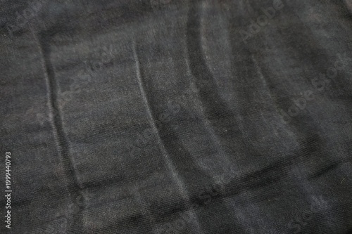 Detailed background of faded crease lines on black denim fabric texture.