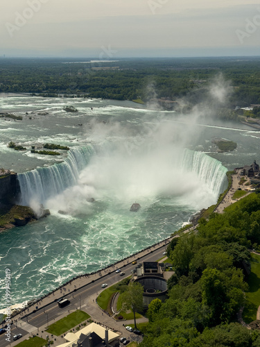 A tour boat loaded with tourists in red ponchos cruises towards the mist at the base of the Horseshoe Falls in Niagara Falls, Ontario, Canada.