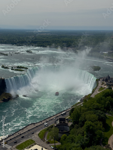A tour boat loaded with tourists in red ponchos cruises towards the mist at the base of the Horseshoe Falls in Niagara Falls, Ontario, Canada.