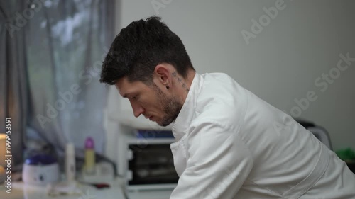 Profile view of a professional male physiotherapist giving a back massage in a tranquil wellness spa salon. He is focused on his work