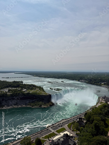 A tour boat loaded with tourists in red ponchos cruises towards the mist at the base of the Horseshoe Falls in Niagara Falls, Ontario, Canada.