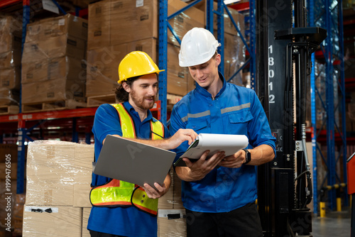 Canvastavla Male warehouse staff and supervisor reviewing logistics documents and shipment details together using clipboard and laptop