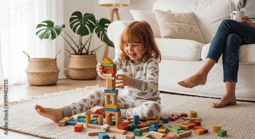 Happy toddler girl playing with colorful wooden building blocks