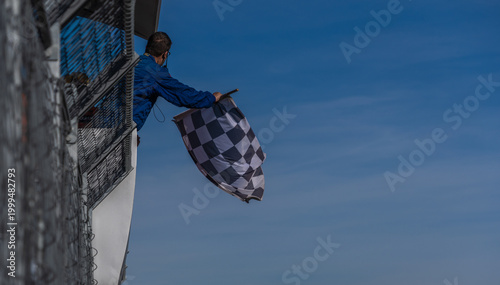 Race marshal waving checkered flag at motorsport finish line