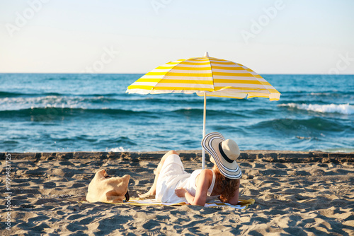 Εκτύπωση καμβά Woman relaxing under beach umbrella looking at the sea