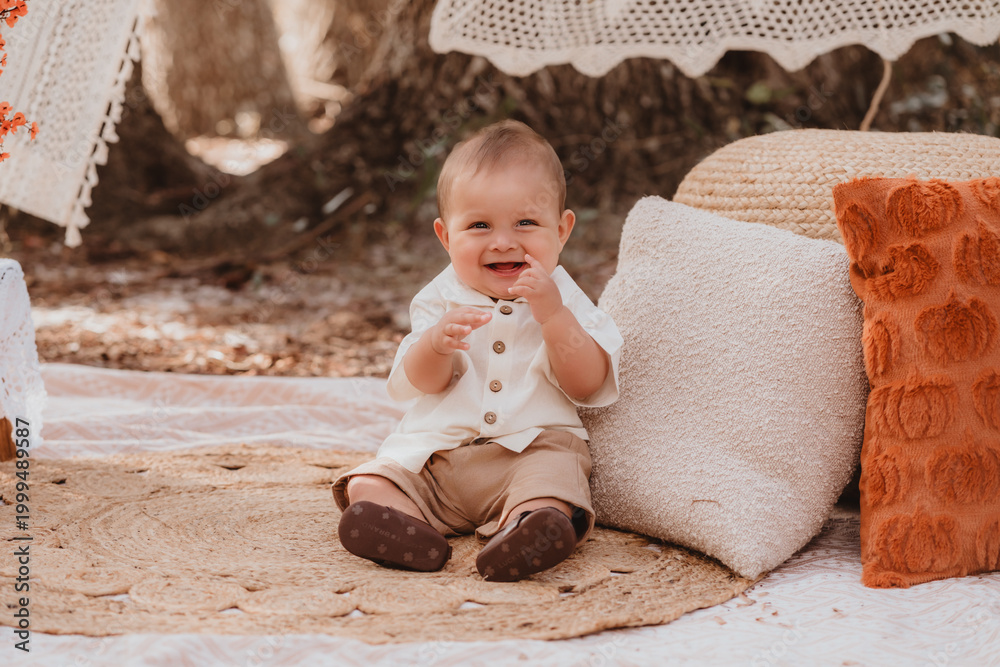 Fototapeta premium Happy mother and toddler son enjoying a bohemian autumn picnic in an outdoor park with pumpkins and fall decor