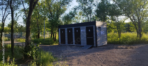 Картината върху платно Modern rectangular public restroom is located in sunlit wooded area
