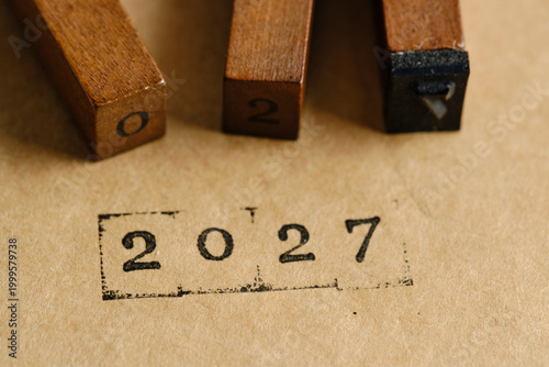 Macro close up wooden blocks and year 2027 stamped on paper.