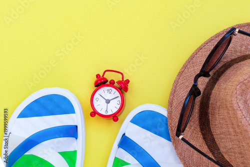 Vertical travel layout with summer essentials and alarm clock on bright yellow.