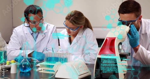 Pipetting, three researchers in lab coats, goggles, gloves working at lab bench with test tube rack